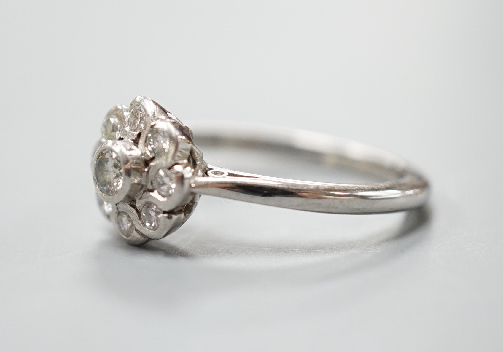 A modern platinum and nine stone diamond set flower head cluster ring, size O, gross weight 5.4 grams.